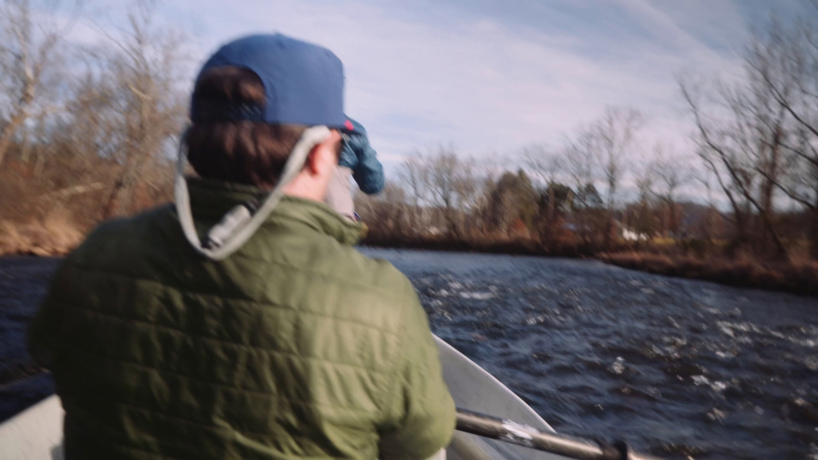 a man in a green jacket in a boat on a river