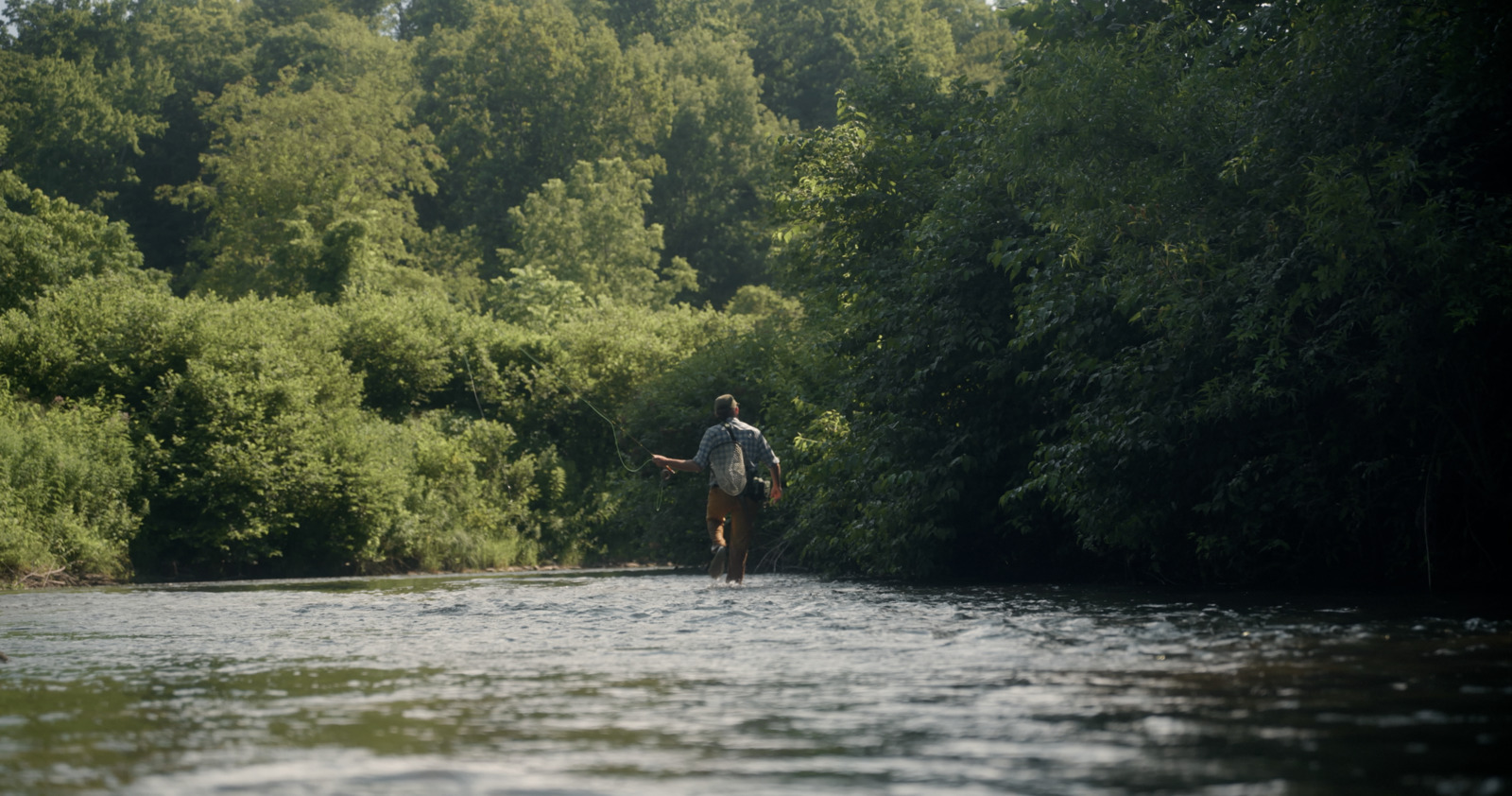 a man standing in the middle of a river holding a fish