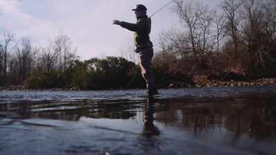 a man standing on a river holding a fishing pole