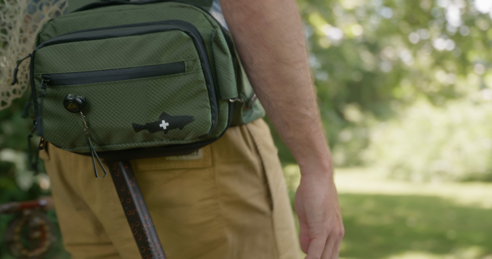 a man carrying a green backpack and walking stick