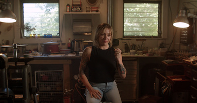 a woman sitting on a stool in a kitchen