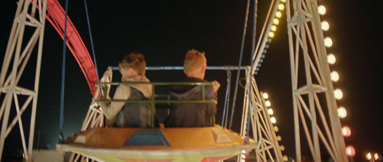 two people sitting on a carnival ride at night