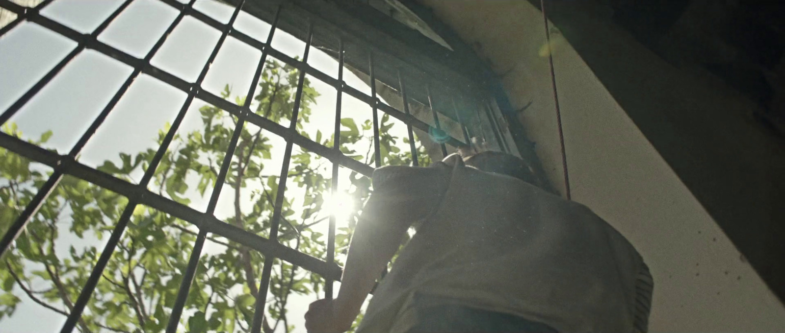 a man standing next to a window with bars on it