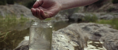 a person is holding a jar with water in it