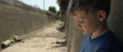 a young boy standing next to a cement wall