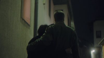 a man and a woman walking down a street at night