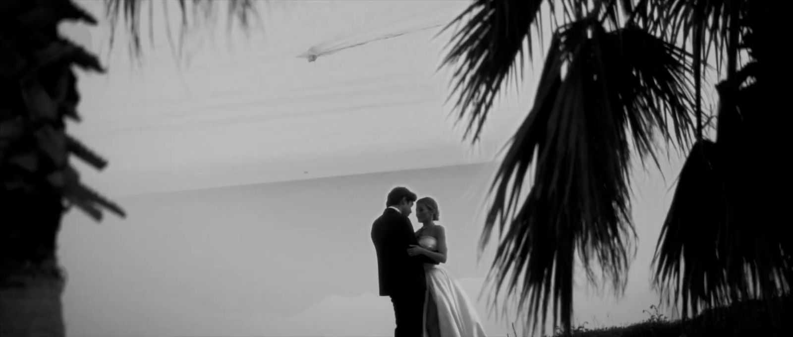 a bride and groom standing in front of a palm tree