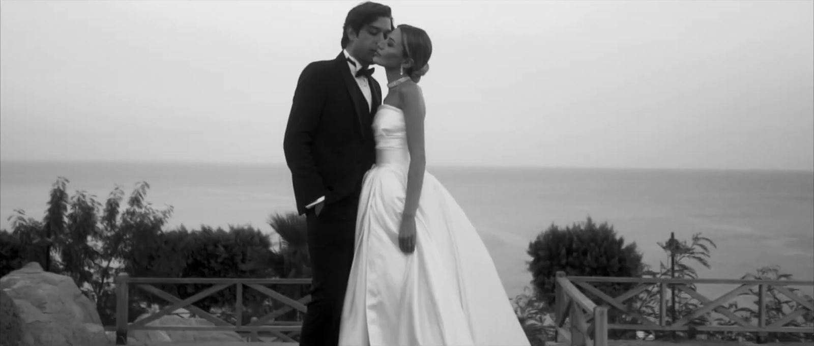 a bride and groom kissing in front of the ocean