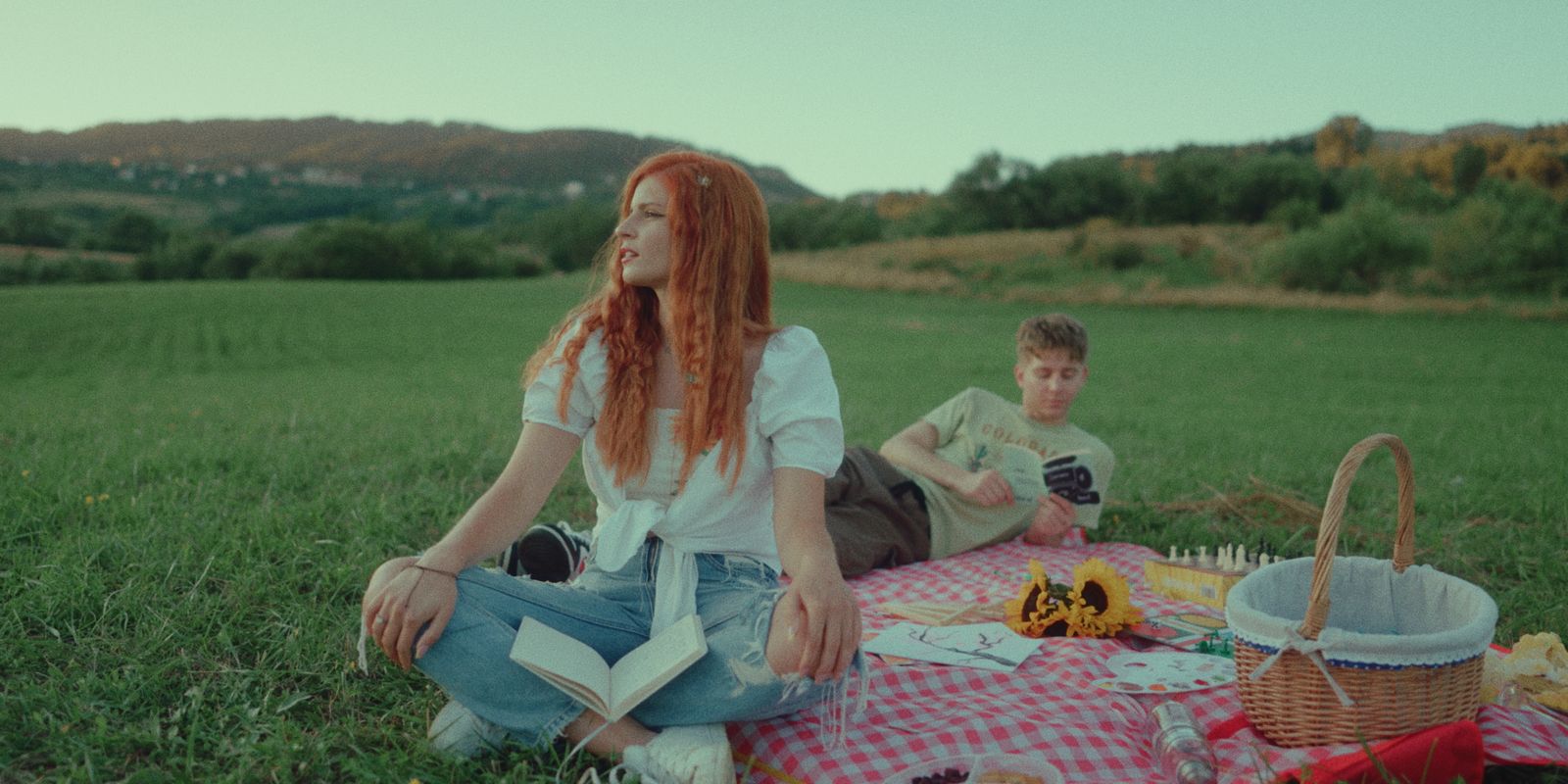 two people sitting on a blanket in a field