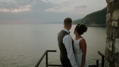 a bride and groom looking out over the water