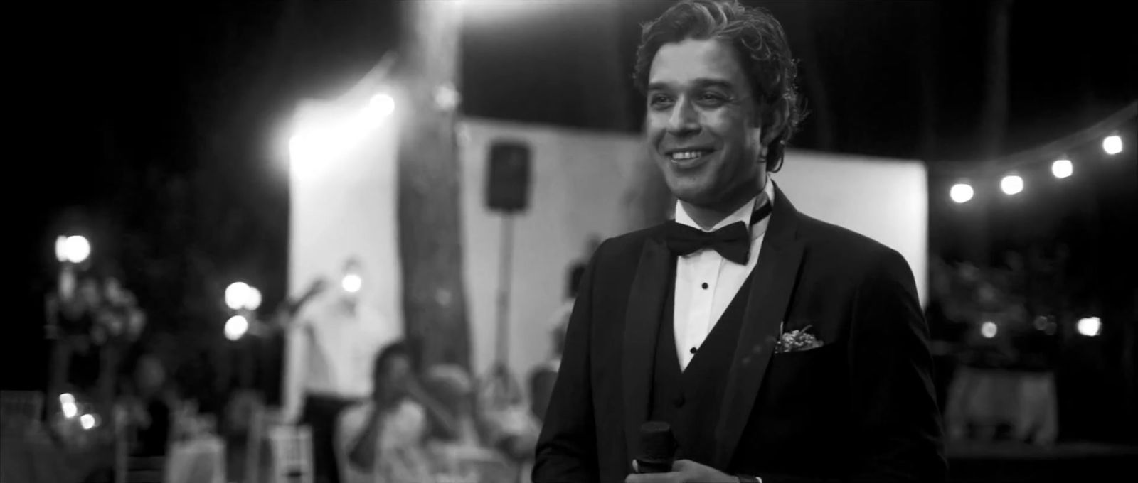 a man in a tuxedo smiles at the camera