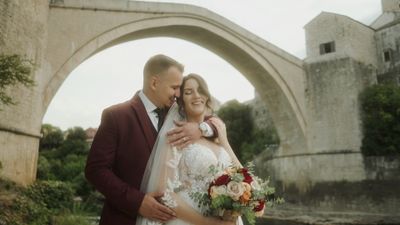 a bride and groom standing in front of a stone arch