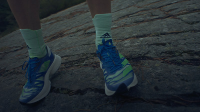 a person wearing blue and green shoes standing on a rock