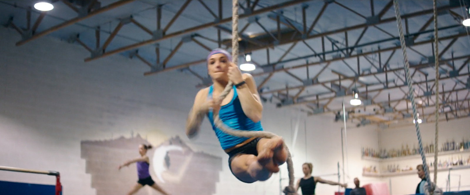 a woman in a blue shirt doing a trick on a trampoline