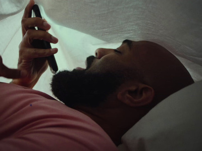 a man laying in bed holding a cell phone