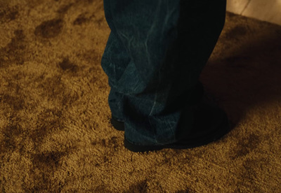 a person standing on a brown carpet with a cell phone in their hand