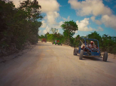 a group of people riding in a buggy down a dirt road