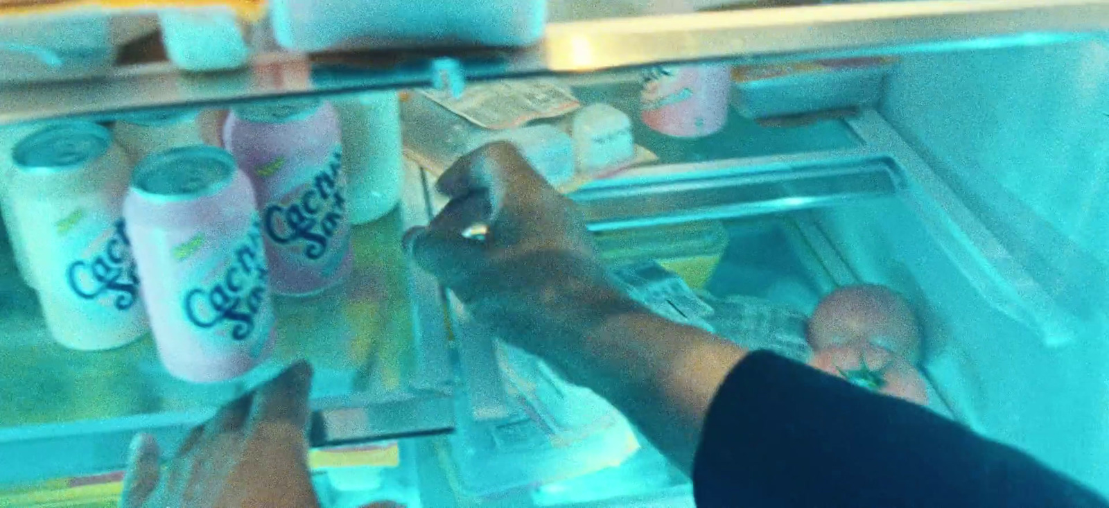 a person reaching for a drink in a refrigerator