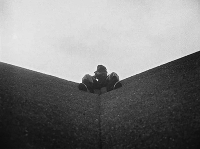 a man sitting on top of a roof next to a skateboard