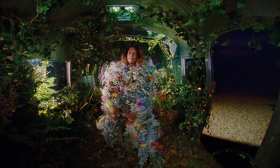 a woman is walking through a garden tunnel