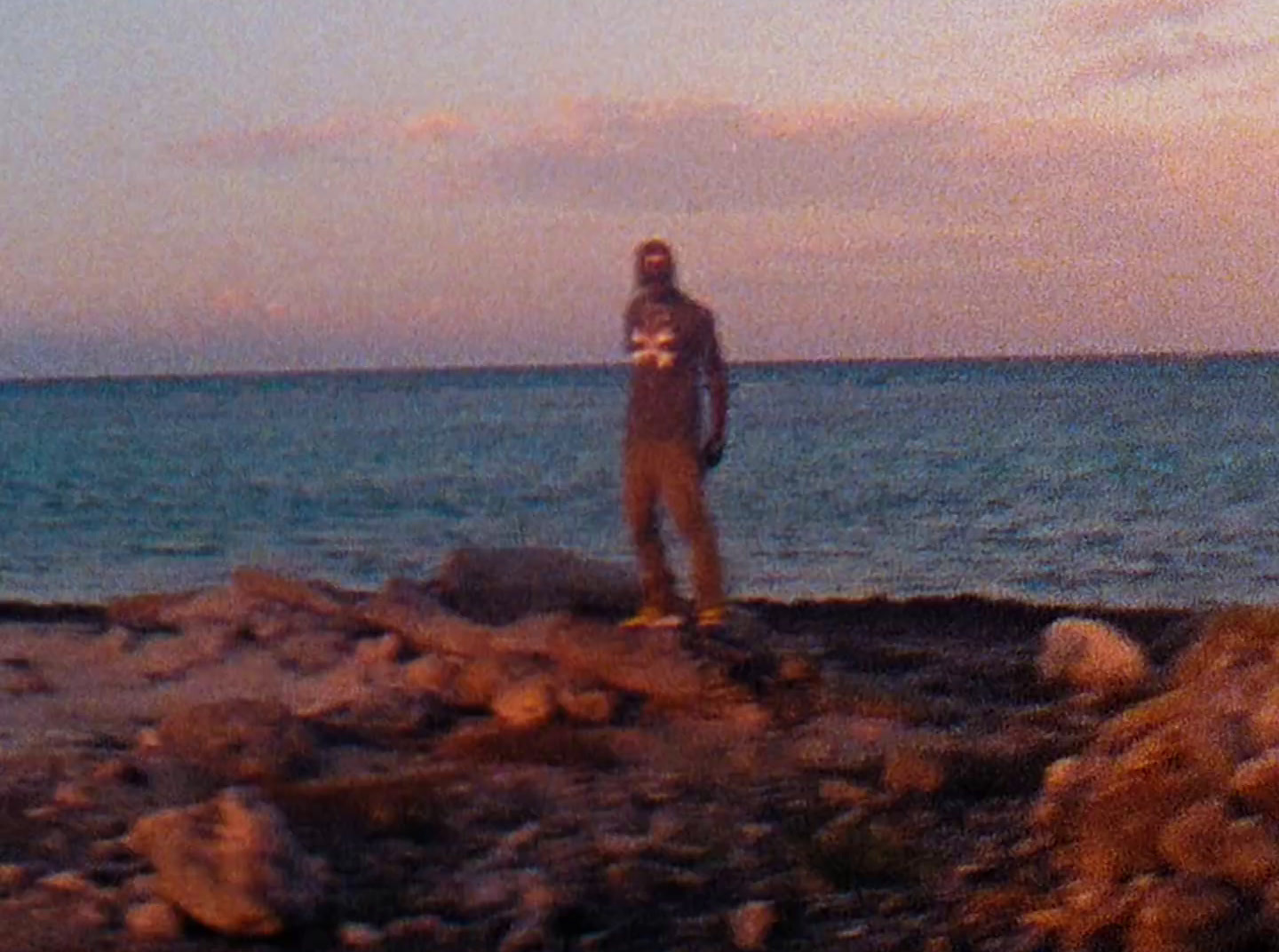 a man standing on top of a rocky beach next to the ocean