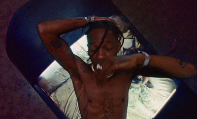 a man with tattoos on his chest laying on a bed