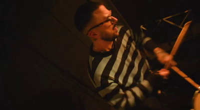 a man in striped shirt playing drums in a dark room