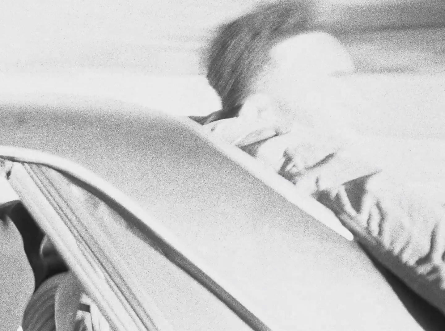 a black and white photo of a person sleeping in a car