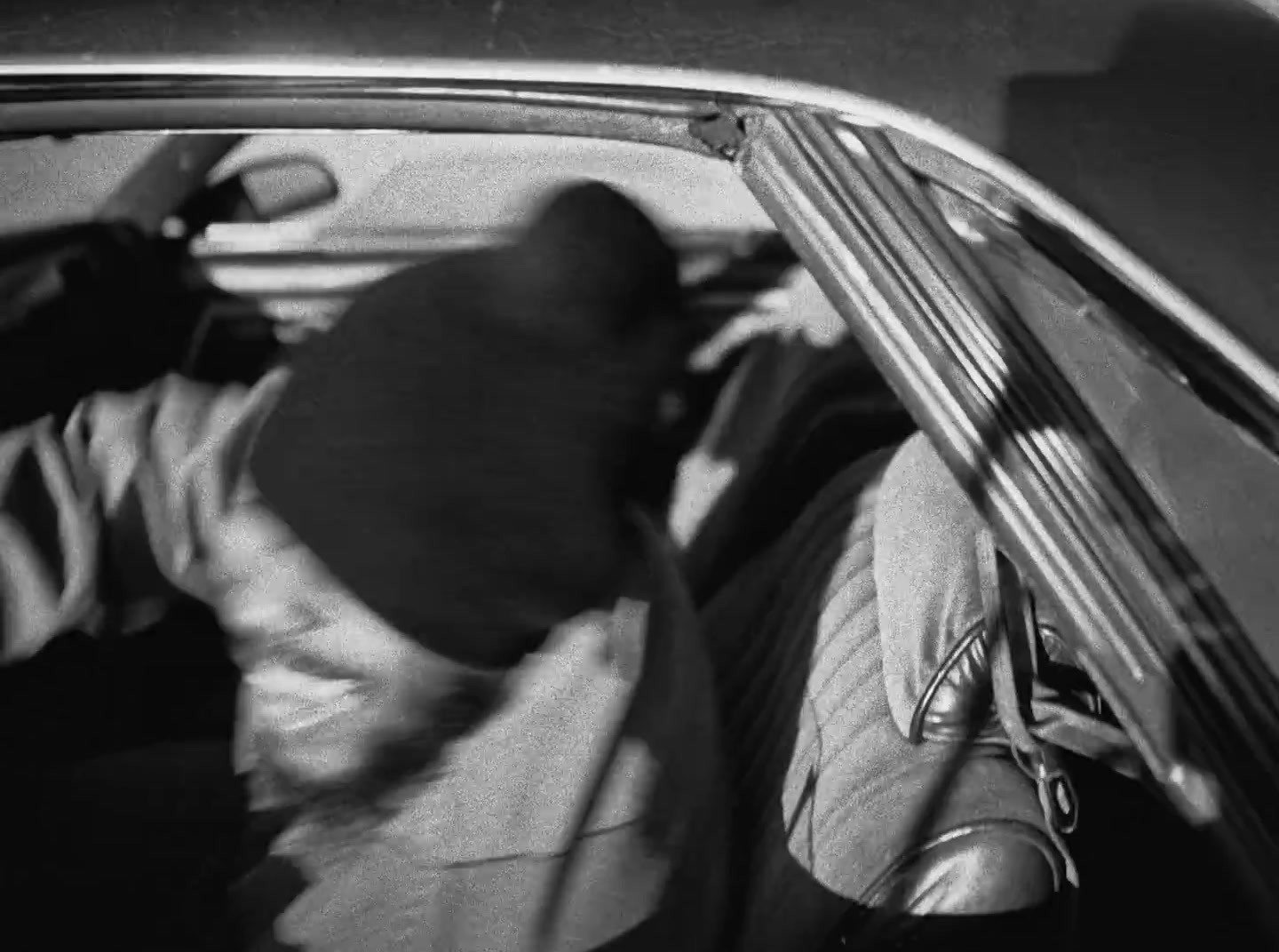 a black and white photo of a man in a car