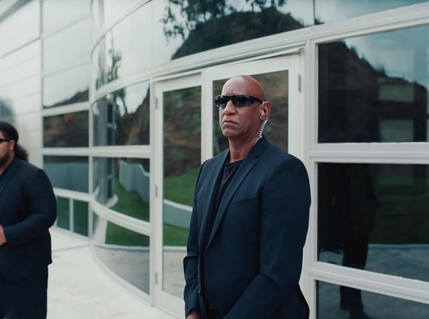 a man in a suit and sunglasses standing in front of a building