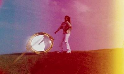 a woman standing on top of a hill next to a mirror