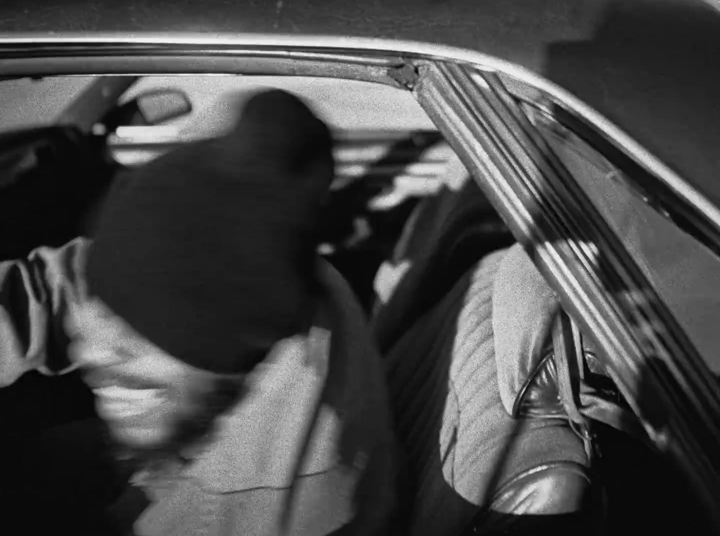 a black and white photo of a man sitting in a car