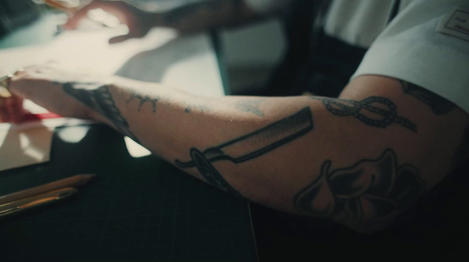 a man with a tattoo on his arm sitting at a desk