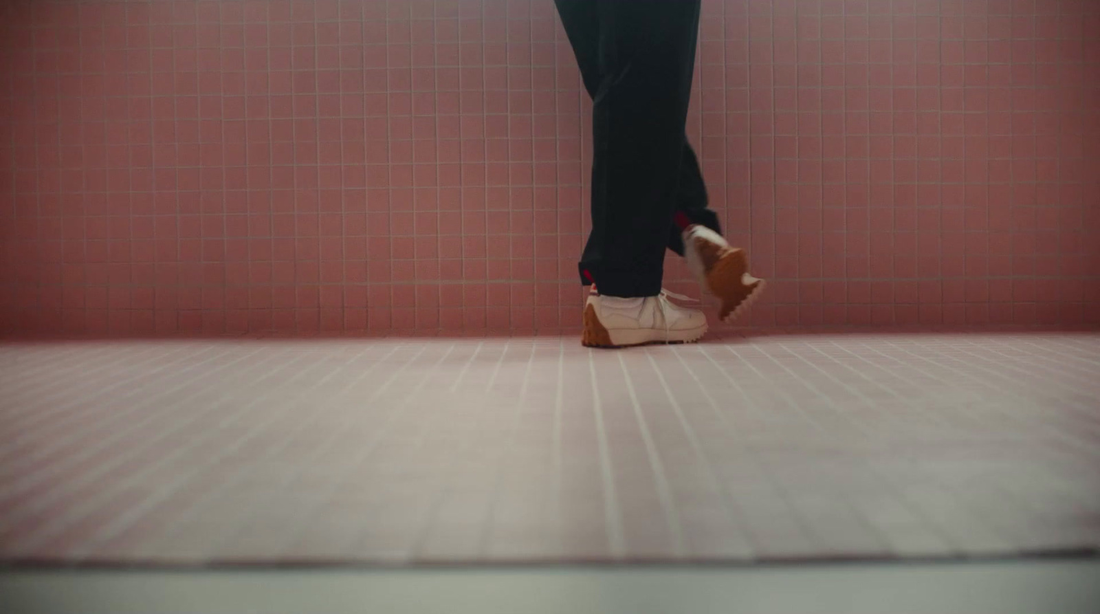 a person standing in front of a pink tiled wall