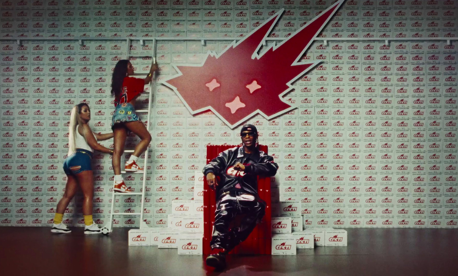 a man sitting on a red chair next to two women