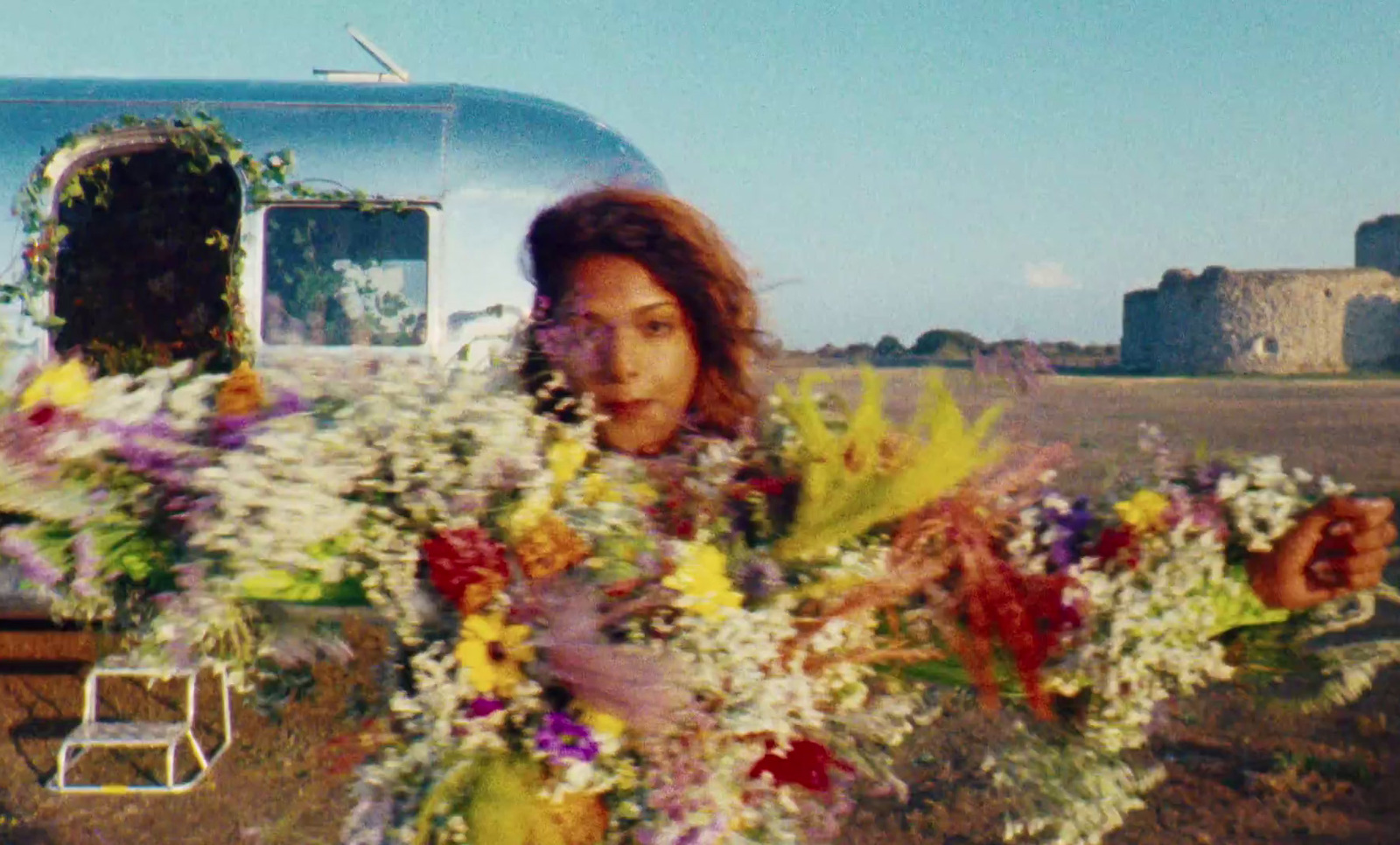 a woman holding a bouquet of flowers in front of a trailer