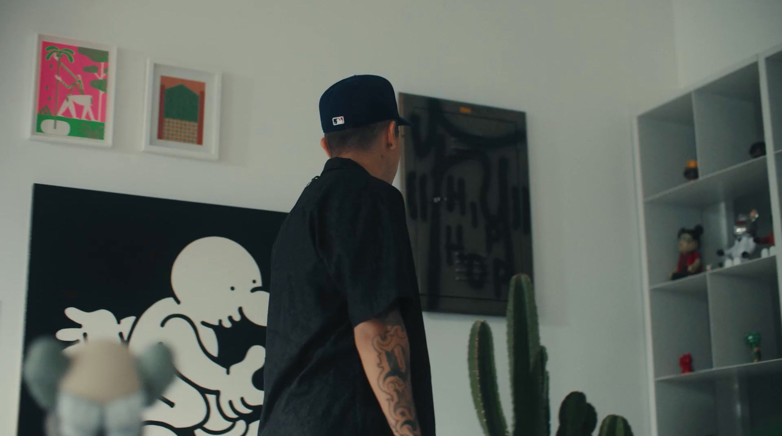 a man standing in a living room next to a cactus