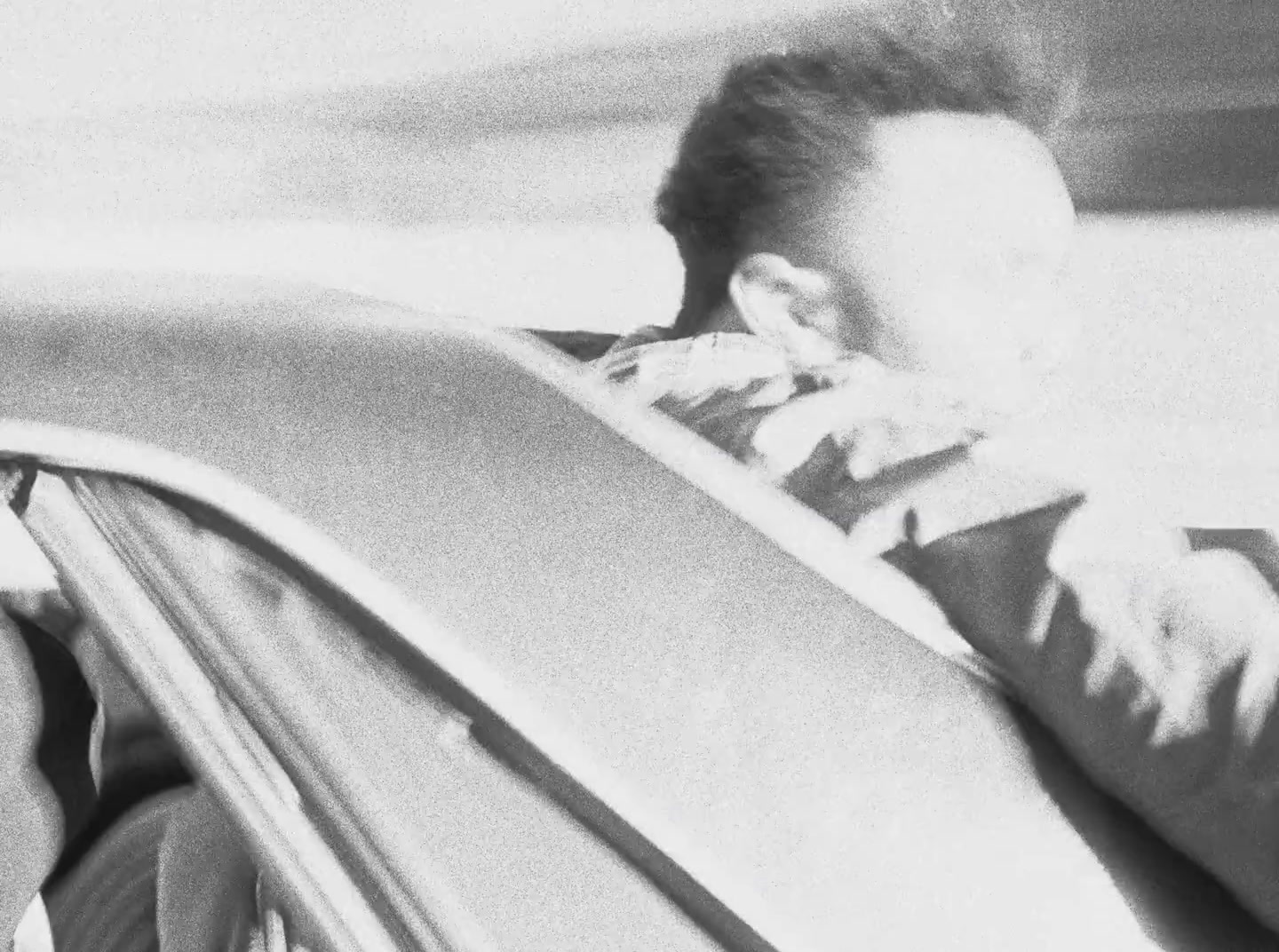 a black and white photo of a woman sitting in a car