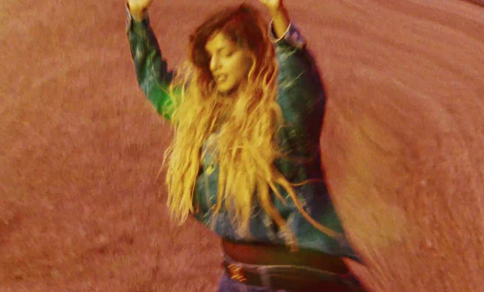 a woman with long hair standing on a dirt road