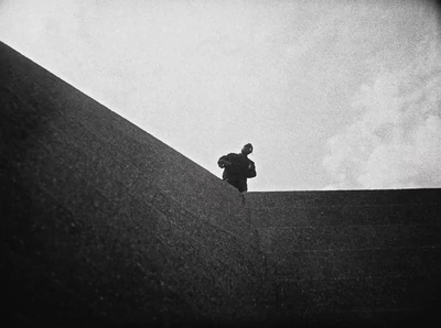 a black and white photo of a person standing on a ledge