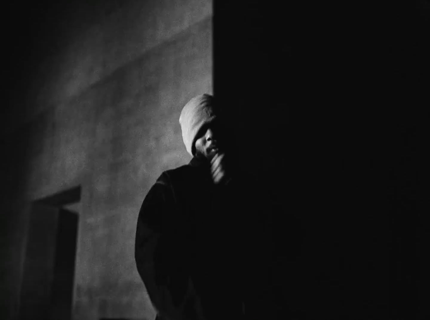 a man standing in a dark room with his hand on his face