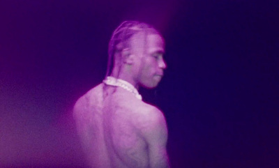 a man with long hair standing in a dark room