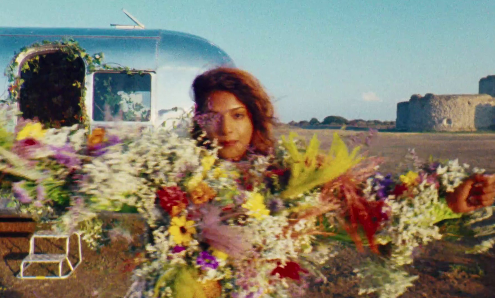 a woman holding a bouquet of flowers in front of a trailer