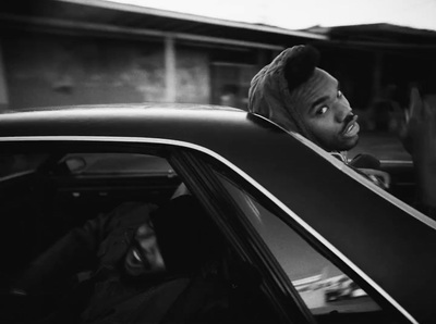 a black and white photo of a man sticking his head out of a car window