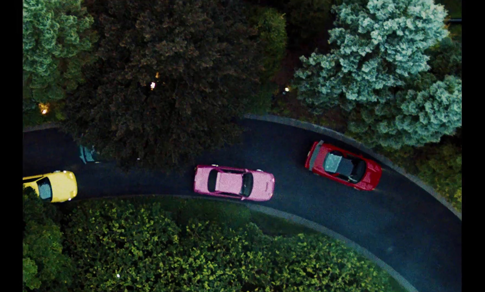 three cars are parked on a curved road