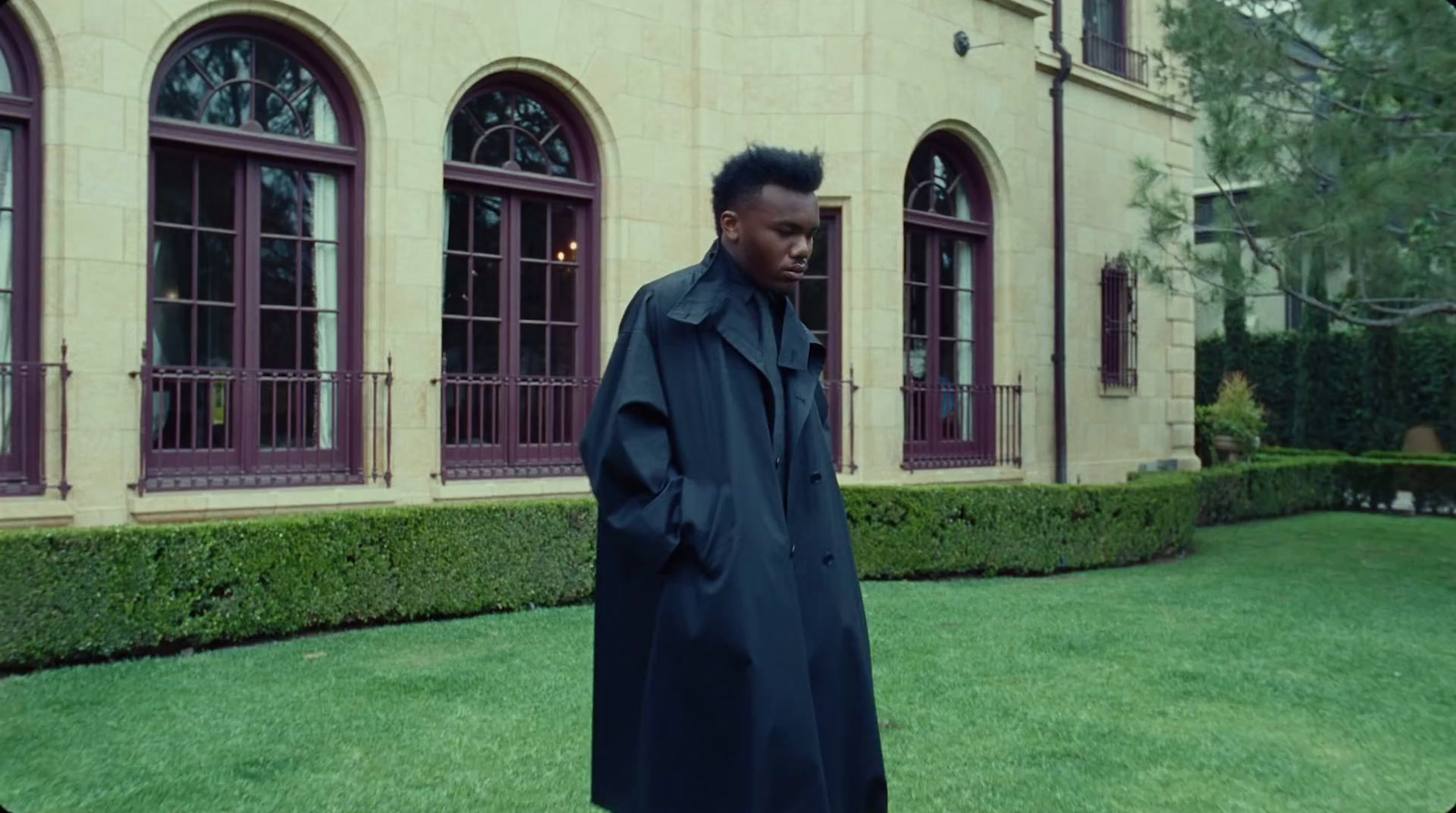 a man in a trench coat standing in front of a building