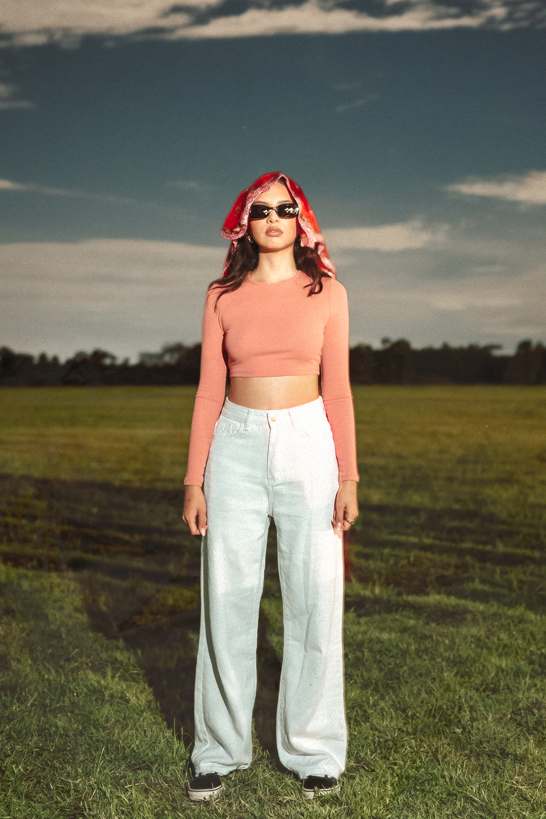 a woman standing in a field with a red bandana on her head