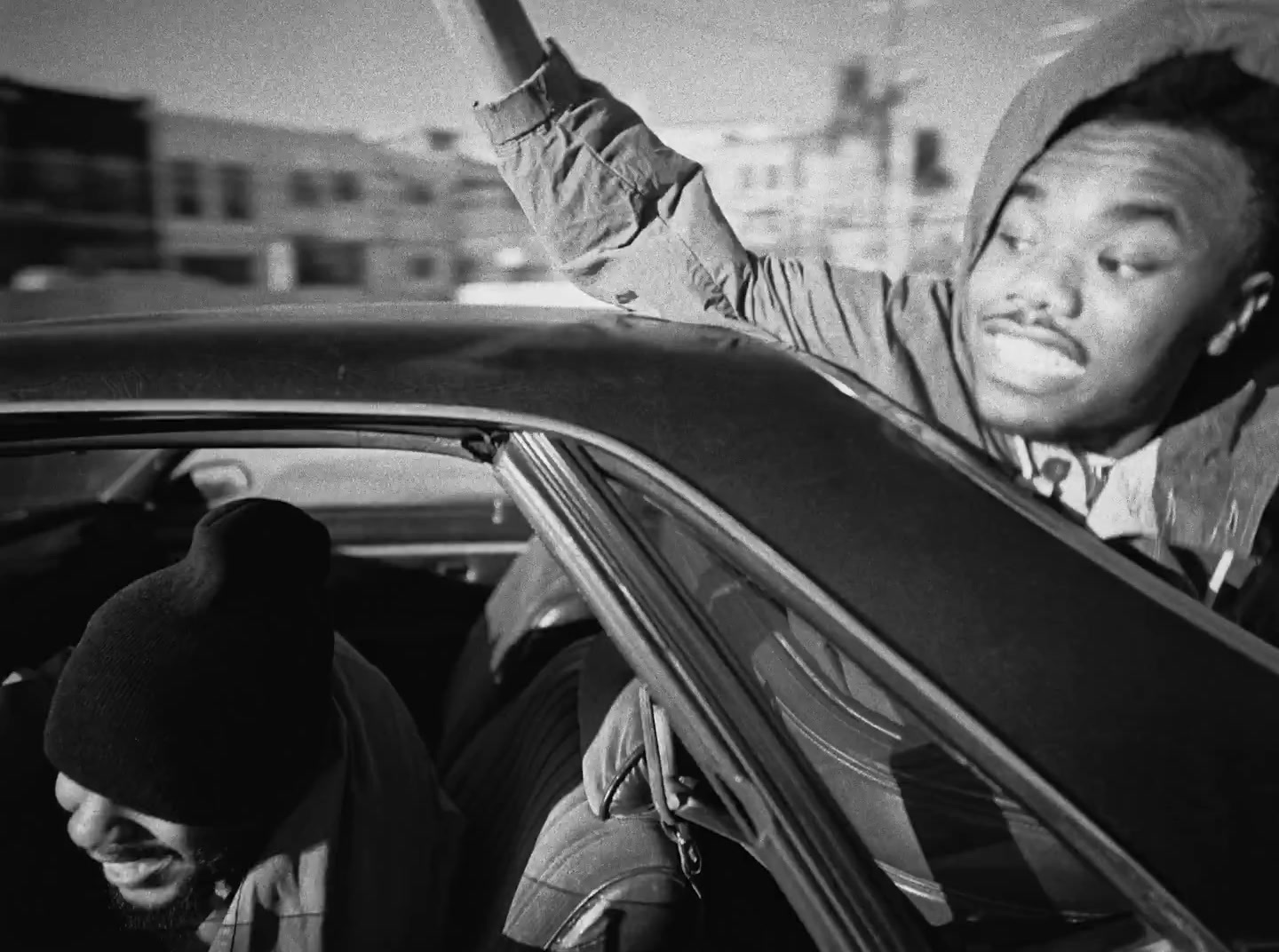 a black and white photo of a man sitting in a car