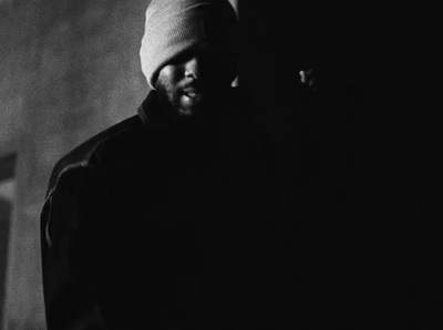 a man in a beanie standing in a dark room