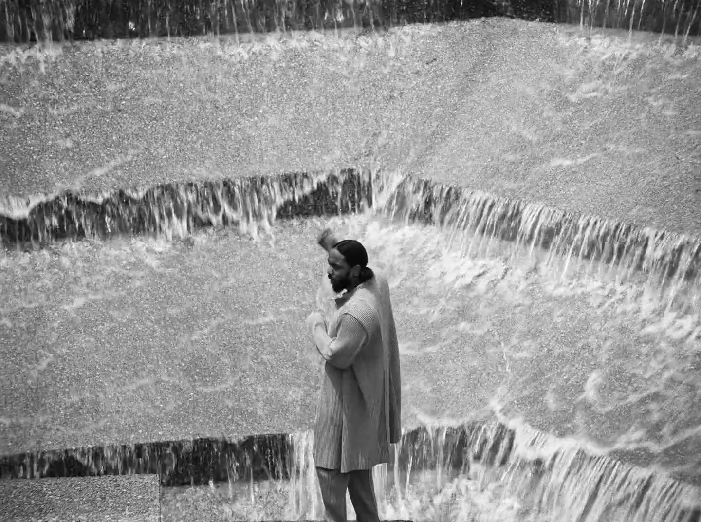 a man standing in front of a waterfall talking on a cell phone